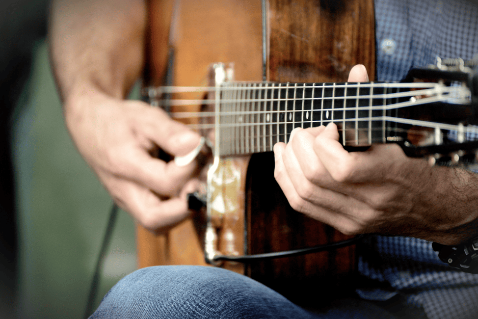 Person playing guitar and listening to music, illustrating music as one of the 10 Most Popular Hobbies in the World for creativity and joy.