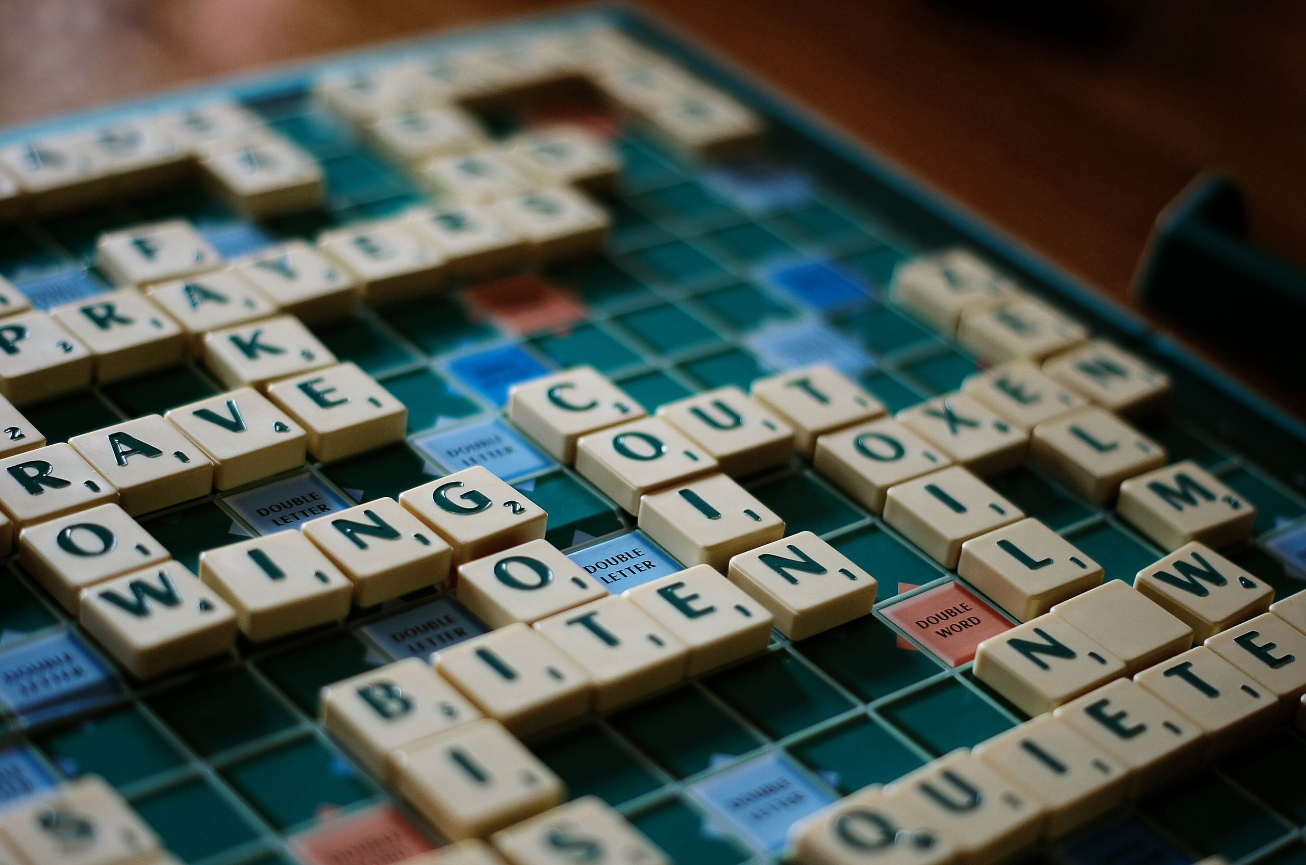 Scrabble game in play with letter tiles forming words from the 10 Most Popular Board Games in the World.