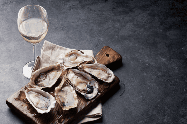 Delicate shellfish and creamy Brie paired with white wine in the Luxury Fine Wines and Spirits Buying Guide for refined palates.